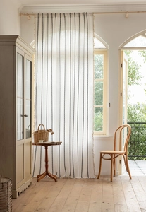 Détail d'un rideau en lin blanc semi-transparent avec rayures et bordures à glands