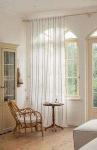 Detail of white semi-sheer linen curtain with blue chain patterns and side tassel trim