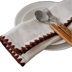 White fabric table runner with brown triangular embroidery and rustic cutlery setting