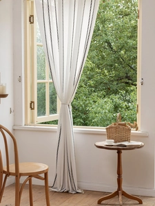 Détail du rideau en lin blanc semi-transparent avec coutures noires et pompons
