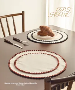 Macro shot of round linen table mats with exquisite floral embroidery edge on wooden table