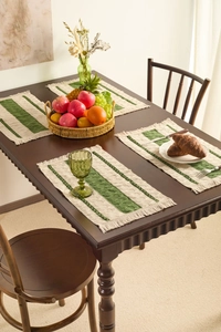 Close-up of four-piece striped woven placemats with fringe on a wooden dining table