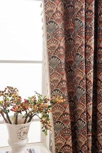 Detail eines Vintage-Jacquard-Vorhangs mit Retromustern und cremefarbenen Quastenfransen