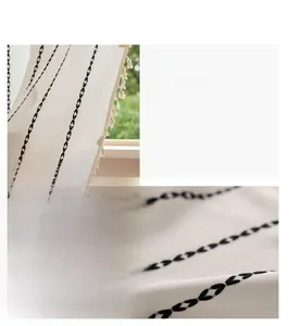 Vue macro détaillée du rideau en lin beige avec broderie noire et pompons de couleur crème