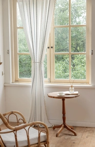 Close-up of white semi-sheer linen curtain with black diamonds and tassel edge