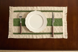 Close-up of bohemian woven placemat with green stripes and handmade tassel details