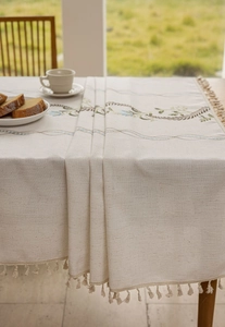 Detail view of cotton linen tablecloth featuring floral embroidery and fringe tassels