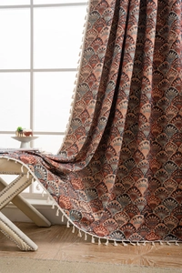 Detail eines Jacquard-Vorhangs im Boho-Stil mit Fächermuster und weißen Baumwollquasten