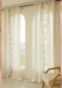 Close-up of pink flower embroidery and tassel fringe on beige cotton linen curtains