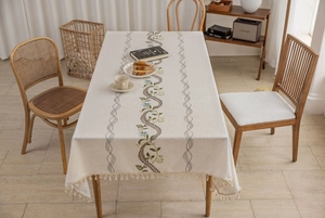 Detailed view of floral embroidery and handmade tassels on beige cotton linen tablecloth