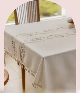 Close-up of beige cotton linen tablecloth with floral embroidery and tassel details