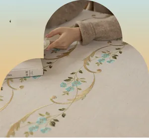 Close-up of beige linen tablecloth with elegant floral embroidery and vintage tassels