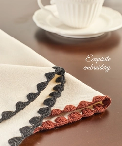 Detailed close-up of cotton linen placemat with hand-stitched embroidery and wavy edges