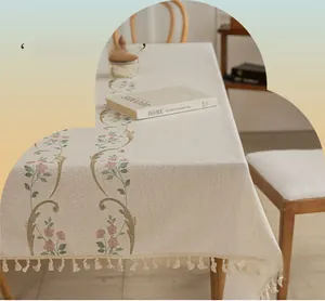 Close-up of linen tablecloth with pink floral embroidery and delicate fringe edges