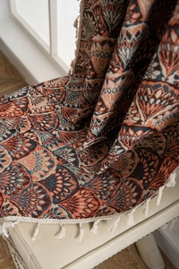 Detailansicht von Boho-Jacquard-Stoff mit orange-blauen Mustern und cremefarbenen Quasten