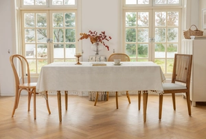 Detail of embroidered beige linen tablecloth featuring elegant fringe tassels on the edge
