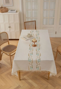 Detail of French floral embroidery and elegant cream fringe on a linen tablecloth