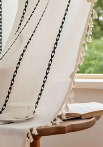 Détail du tissu en lin de coton bohème avec broderie noire et glands à franges