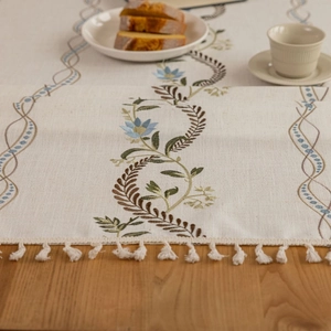 Linen table runner with blue flower embroidery and beige tassels for dining table