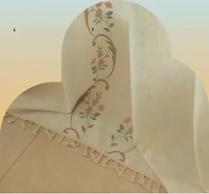 Detail of beige cotton linen curtain with floral embroidery and decorative tassel fringe
