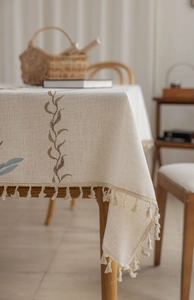Detail of embroidered vine patterns and fringe tassel edge on linen blend tablecloth