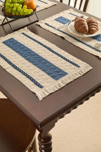 Detailed close-up of woven cotton table mat with blue stripes and decorative fringe