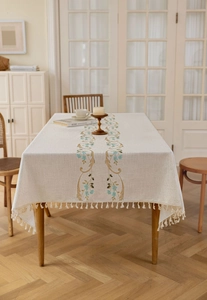 Close-up of elegant floral embroidery and fringe detail on a linen blend tablecloth