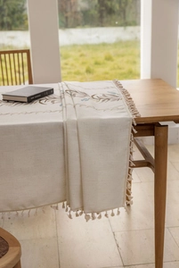 Detail of leaf embroidery and fringe edges on premium off-white linen tablecloth