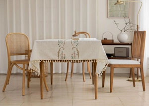 Detail of floral embroidery and fringe tassels on a linen rectangular tablecloth