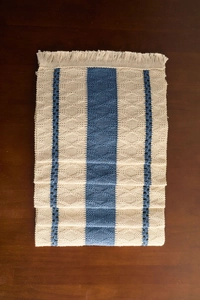 Detail of woven table runner with blue geometric patterns and fringed tassel edges