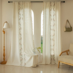 Detailed embroidery of floral vines and delicate tassel edges on linen curtains