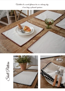 Detailed view of linen placemats with brown shell pattern stitched edges and wavy texture