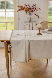Detail of floral embroidery and handmade tassels on beige linen table runner fabric