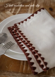 Detailed macro view of the cream cotton linen placemat with red-brown shell embroidery