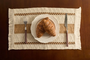 Close-up of bohemian hand-woven placemat featuring geometric patterns and fringe edges