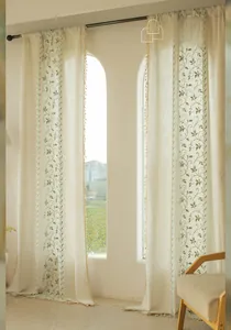 Detail of floral embroidery and beige tassel trim on vintage linen curtains