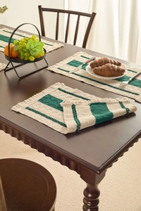 Detail of dark green striped woven placemat with fringe on a wooden table setting