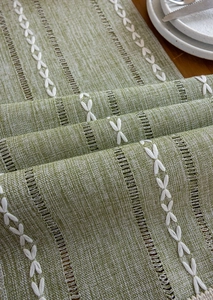 Detailaufnahme von grünem Tischläufer mit Leinentextur und weißen Schleifenmotiven