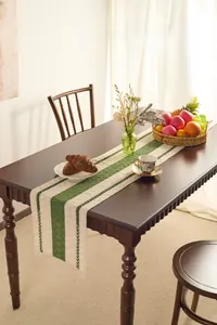 Detail of a Nordic woven table runner with green stripes and tassels on a wooden table