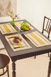 Close-up of Nordic woven placemats with yellow stripes and tassels on a wooden table