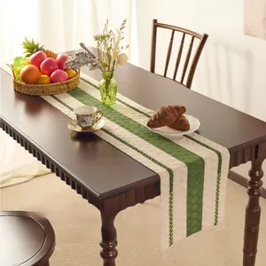 Detailed close-up of woven cotton linen table runner with green stripes and fringe trim