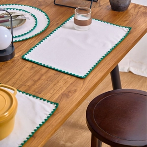Nordic style green embroidered fabric placemat set on a wooden table for dining