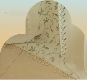 Detail of embroidered green vine patterns on beige curtain with tassel fringe