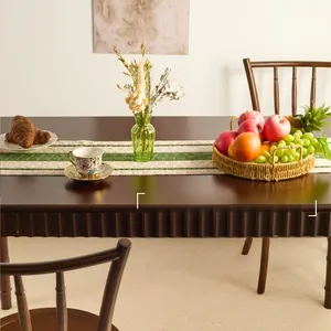 Close-up of woven table runner with green and beige stripes on dark wooden table