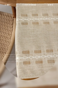 Macro shot of beige table runner with white diamond embroidery and openwork texture