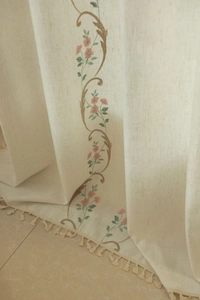 Detailed embroidery of pink flowers and tassels on beige textured linen curtain