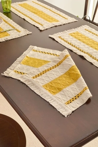 Close-up of yellow and beige hand-woven placemat with fringe and diamond patterns