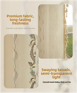Detail of embroidered floral patterns and beige tassels on cream semi-sheer linen curtain