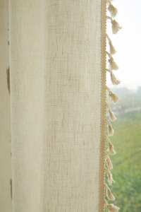 Detailed macro view of beige linen curtain texture with decorative bohemian style tassels