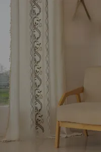 Detail of floral embroidery on light beige linen curtain with decorative fringe edges